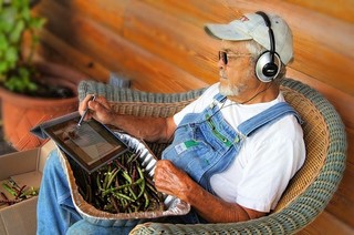 farmer with basket of beans on lap, iPad and headphones