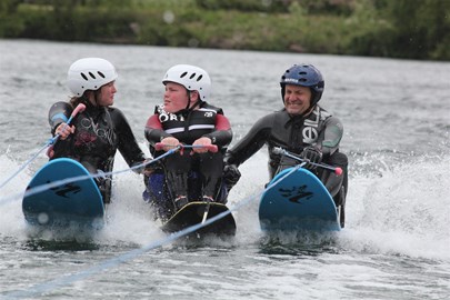 3 water skiers, 2 guiding disabled skier