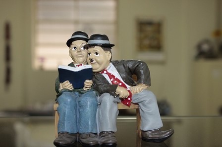 figurine of two men, one reading while other leans in to read with him