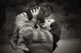 woman holding infant in air and kissing
